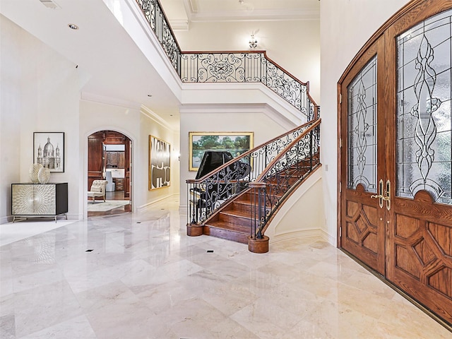 entryway with french doors, ornamental molding, and a high ceiling