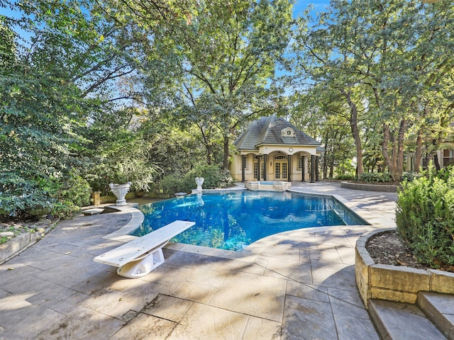 view of pool with a diving board, an outbuilding, and a patio area