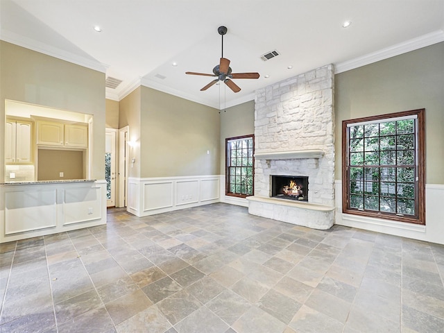 unfurnished living room featuring a stone fireplace, plenty of natural light, crown molding, and ceiling fan