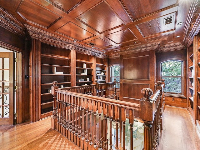 interior space featuring wooden walls, wood ceiling, coffered ceiling, and ornamental molding