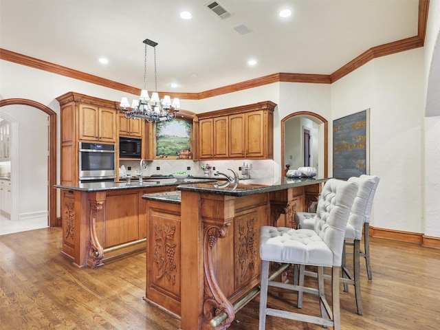 kitchen with pendant lighting, a breakfast bar area, black microwave, a kitchen island, and oven