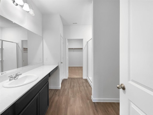 bathroom with hardwood / wood-style flooring, vanity, and a shower with shower door