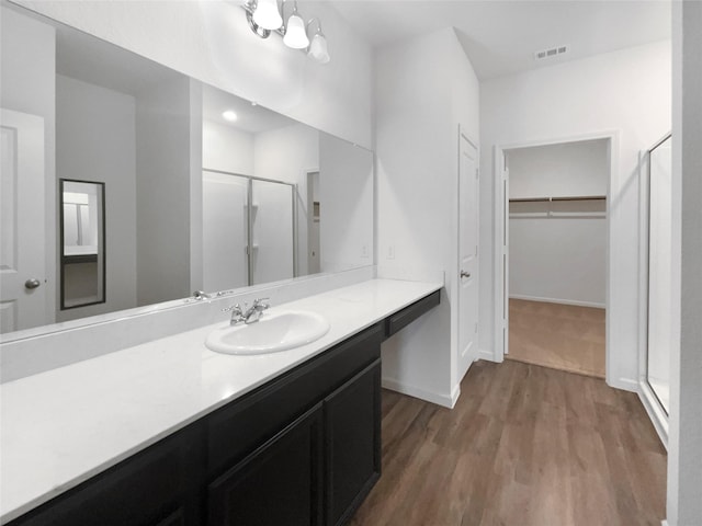 bathroom with walk in shower, vanity, an inviting chandelier, and hardwood / wood-style flooring