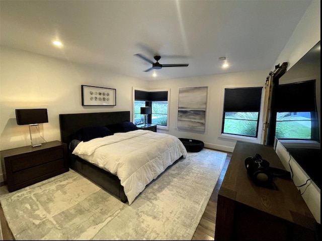 bedroom featuring a barn door, light hardwood / wood-style flooring, and ceiling fan