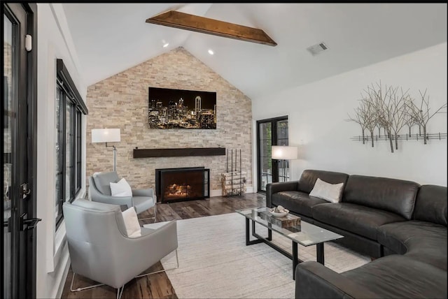 living room featuring beam ceiling, high vaulted ceiling, a stone fireplace, and wood-type flooring