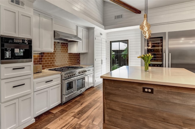 kitchen featuring dark hardwood / wood-style flooring, ventilation hood, double oven range, white cabinets, and hanging light fixtures