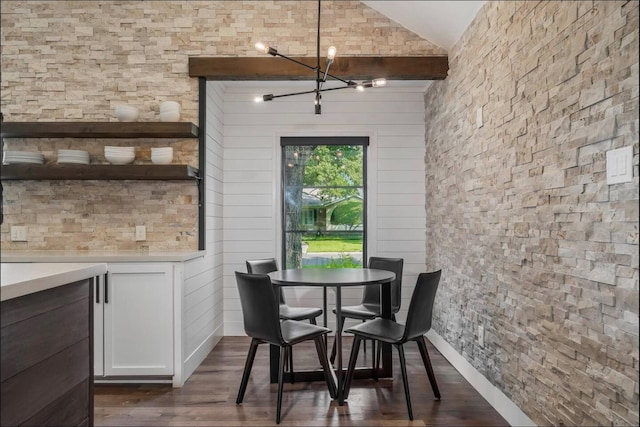 dining space featuring dark hardwood / wood-style flooring, an inviting chandelier, lofted ceiling, and wood walls