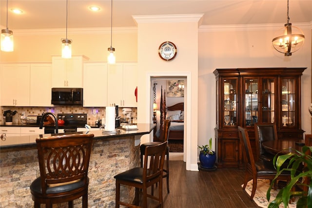 kitchen with a breakfast bar, hanging light fixtures, and white cabinets