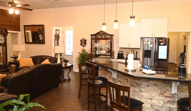 kitchen featuring pendant lighting, white cabinetry, a kitchen bar, stainless steel refrigerator with ice dispenser, and dark wood-type flooring