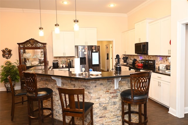 kitchen featuring hanging light fixtures, white cabinetry, a kitchen bar, and black appliances