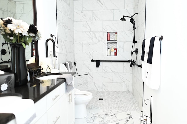 bathroom featuring tiled shower, vanity, and toilet