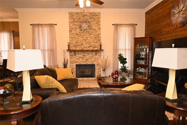 living room with crown molding, a stone fireplace, and ceiling fan