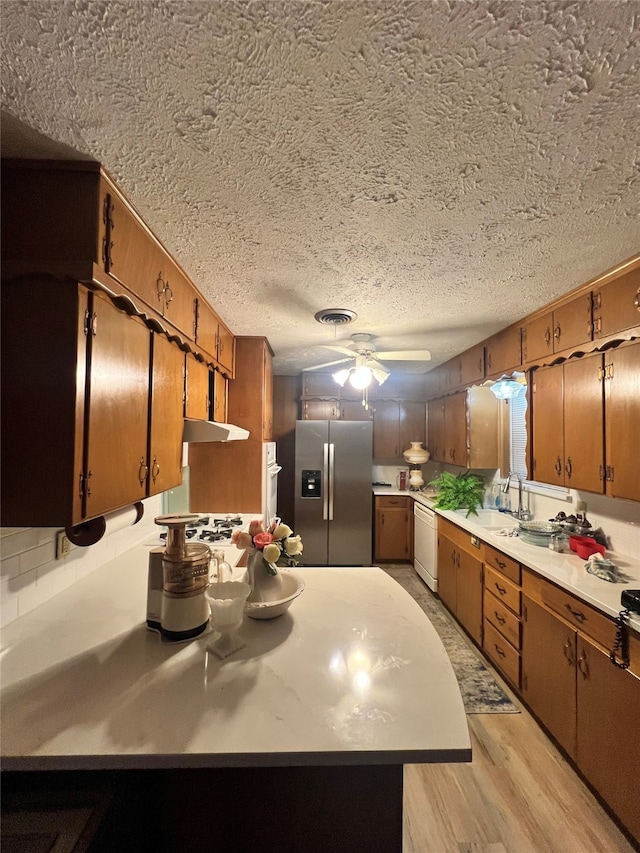 kitchen with ceiling fan, sink, stainless steel fridge with ice dispenser, white dishwasher, and light wood-type flooring