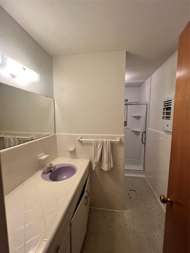 bathroom featuring vanity, a shower with shower door, and tile walls