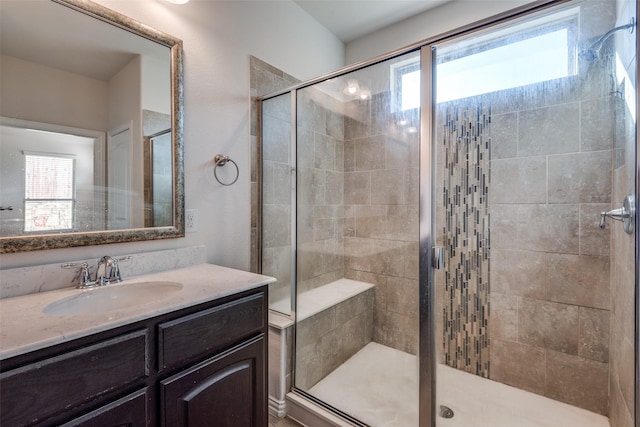 bathroom featuring vanity, a healthy amount of sunlight, and walk in shower