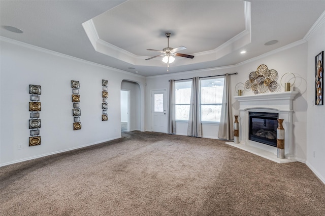 unfurnished living room with carpet flooring, ceiling fan, a raised ceiling, and ornamental molding