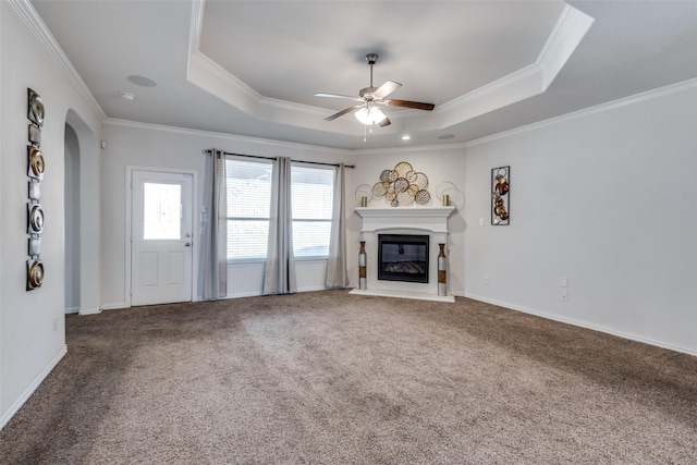 unfurnished living room with carpet flooring, a tray ceiling, ceiling fan, and ornamental molding