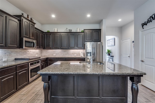 kitchen featuring sink, stainless steel appliances, dark brown cabinets, and light hardwood / wood-style floors