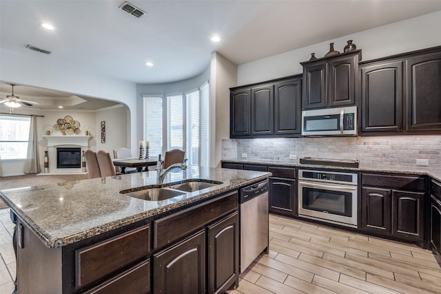 kitchen featuring a center island with sink, sink, ceiling fan, light hardwood / wood-style floors, and stainless steel appliances