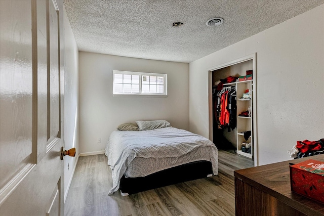 bedroom featuring hardwood / wood-style floors, a textured ceiling, and a closet