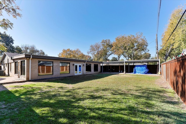 back of house with a lawn, french doors, and a carport