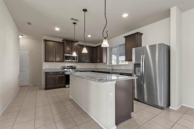 kitchen featuring dark brown cabinetry, a center island, appliances with stainless steel finishes, pendant lighting, and light stone countertops