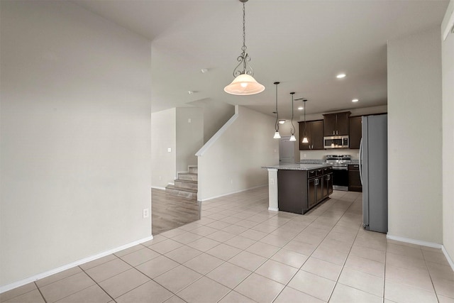 kitchen with dark brown cabinetry, stainless steel appliances, pendant lighting, light tile patterned floors, and a kitchen island