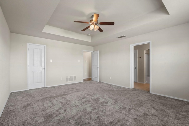 unfurnished bedroom featuring a tray ceiling, ceiling fan, and carpet