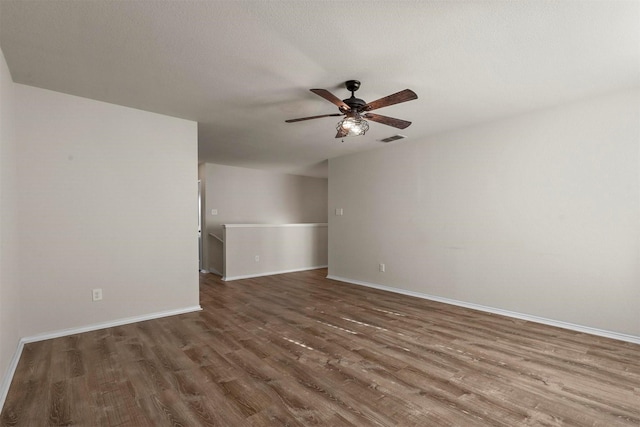 empty room with a textured ceiling, ceiling fan, and dark wood-type flooring