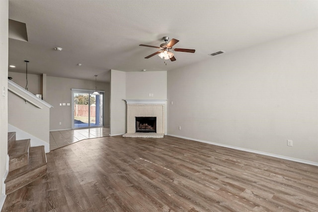 unfurnished living room featuring hardwood / wood-style floors, a brick fireplace, and ceiling fan