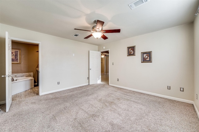 unfurnished bedroom featuring ceiling fan, light colored carpet, and ensuite bath