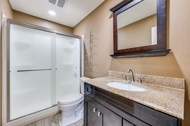 bathroom featuring toilet, vanity, an enclosed shower, and hardwood / wood-style flooring