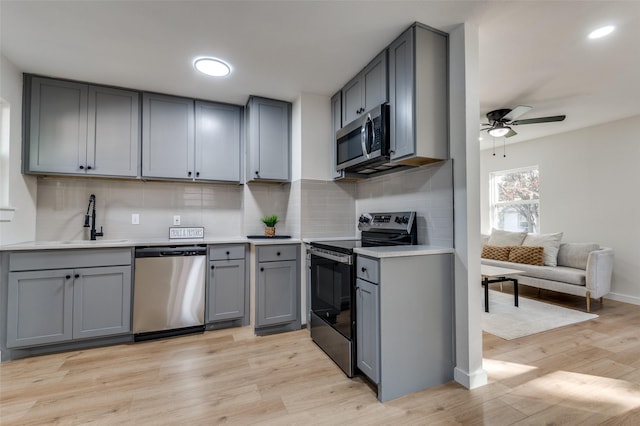 kitchen with gray cabinets, sink, light wood-type flooring, and stainless steel appliances