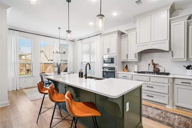 kitchen with visible vents, a sink, stainless steel appliances, light countertops, and backsplash