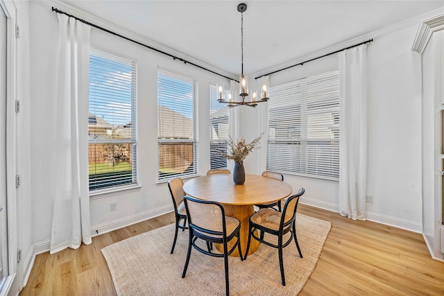 dining area with a wealth of natural light, a notable chandelier, baseboards, and light wood-style floors