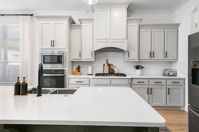 kitchen featuring crown molding, backsplash, appliances with stainless steel finishes, and a sink