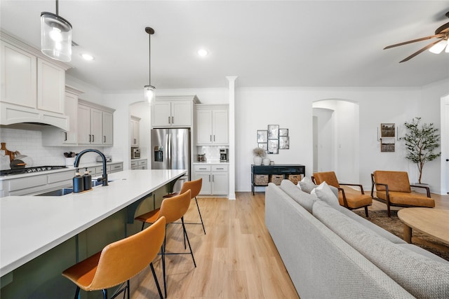 kitchen featuring backsplash, open floor plan, a breakfast bar area, stainless steel refrigerator with ice dispenser, and arched walkways