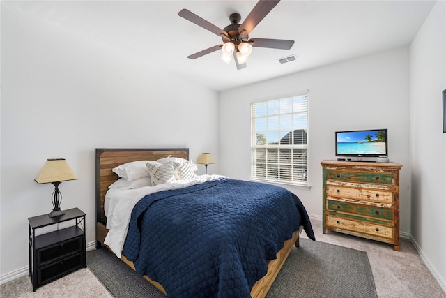 carpeted bedroom with visible vents, baseboards, and a ceiling fan