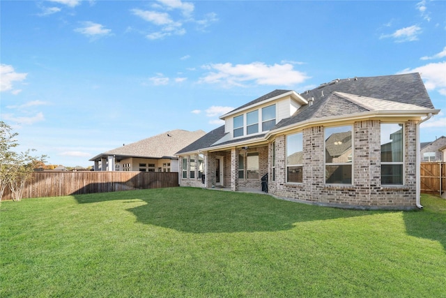 back of property with brick siding, a lawn, and a fenced backyard