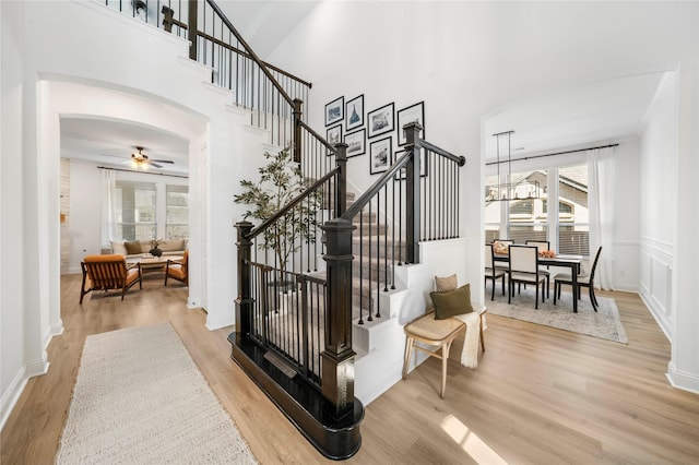 stairway featuring a high ceiling, wood finished floors, arched walkways, and a wealth of natural light