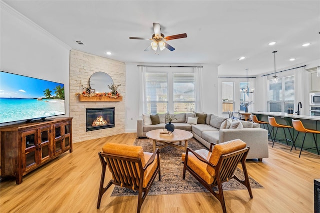 living area featuring visible vents, a fireplace, light wood-type flooring, and crown molding