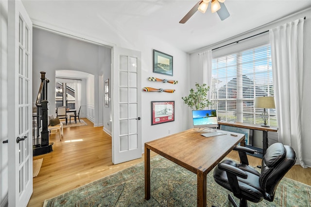 office area with a ceiling fan, light wood-style floors, french doors, and arched walkways