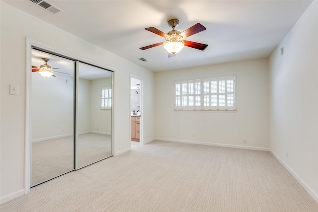 unfurnished bedroom with light carpet, a closet, and ceiling fan