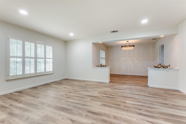 unfurnished living room featuring light hardwood / wood-style flooring and an inviting chandelier