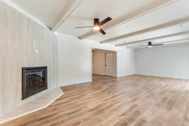 unfurnished living room with ceiling fan, beam ceiling, light wood-type flooring, and a tiled fireplace