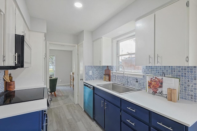 kitchen featuring light wood-type flooring, stainless steel dishwasher, blue cabinets, sink, and white cabinetry