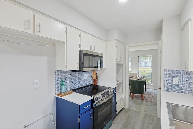 kitchen featuring white cabinets, light wood-type flooring, blue cabinetry, tasteful backsplash, and stainless steel appliances