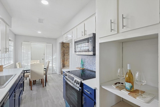 kitchen featuring blue cabinetry, white cabinets, and appliances with stainless steel finishes