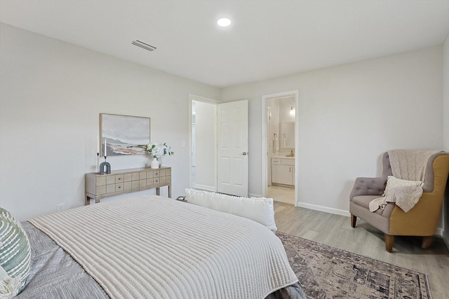 bedroom featuring ensuite bathroom and light wood-type flooring