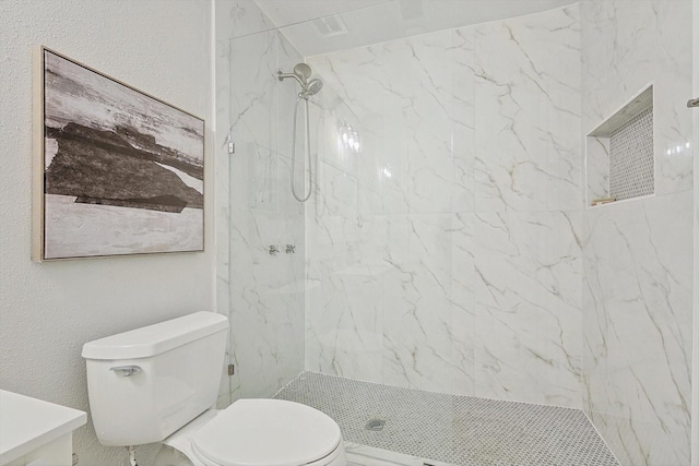 bathroom with a tile shower and toilet